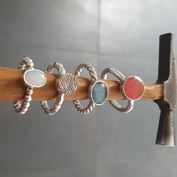 Vier zilveren ringen met steentjes op een houten stok