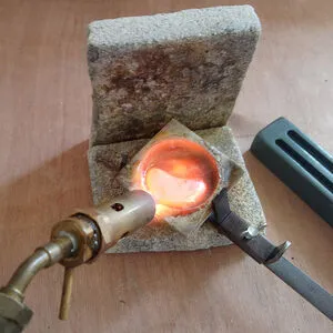 Goud wordt gesmolten in een kroes met een vlam