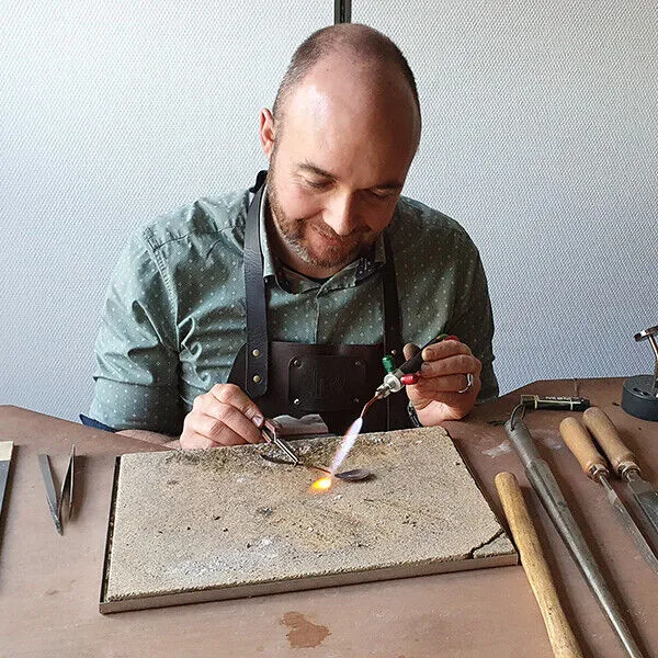 Goudsmid Remco Dijkstra soldeert een sieraad aan zijn werkbank